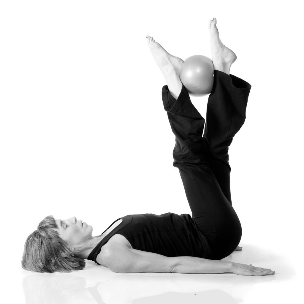 Demonstrating another pilates exercise with a ball.